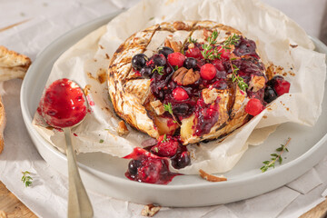 Baked or fried grilled Camembert or brie cheese with berry sauce or jam. Gourmet traditional Breakfast close up.