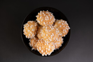 bowl of chouquettes,  french choux pastry isolated on a black background,  french sweet pastry speciality.