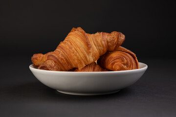 croissant on a white plate isolated on a black background,  french sweet pastry speciality, Breakfast or brunch concept.