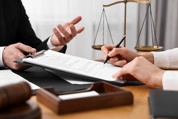 Woman signing document in lawyer's office, closeup