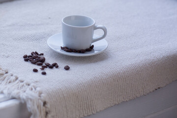 white coffee cup and beans on white tablecloth background close up photo with copy space