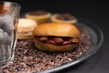 focus on beautiful plate of cookies, macaron, Madeleine and chocolate placed on a black background
