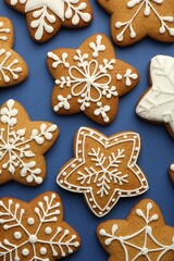 Tasty star shaped Christmas cookies with icing on blue background, flat lay