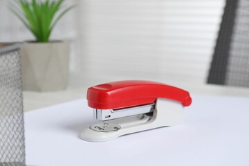 Bright stapler and paper on table indoors, closeup