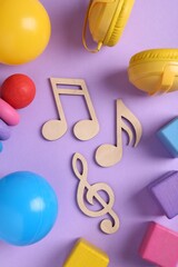 Tools for creating baby songs. Flat lay composition with wooden notes on violet background