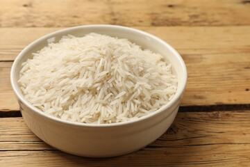 Raw basmati rice in bowl on wooden table