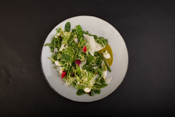 top view on salad with vegetables in a white plate with sauce isolated on a black background