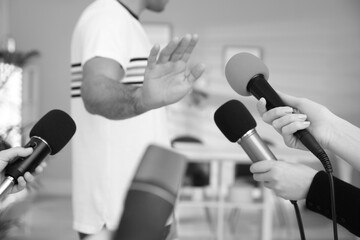 Man avoiding journalist's questions at interview indoors, closeup. Black and white effect