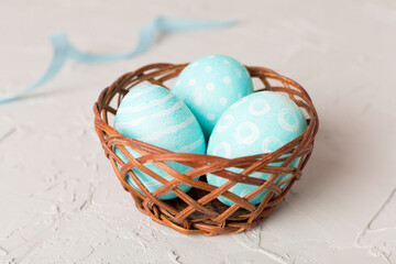 Blue easter eggs in basket on concrete table
