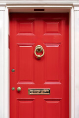 Vibrant red door on a classic white facade, exuding warmth and timeless elegance.
