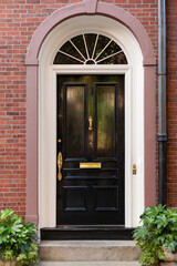A striking black door, embraced by a flowing arch, exudes sophistication and charm.