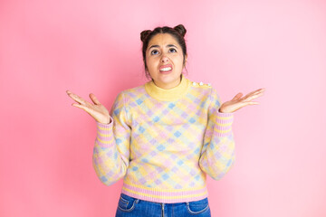 Young beautiful woman wearing casual sweater over isolated pink background clueless and confused...