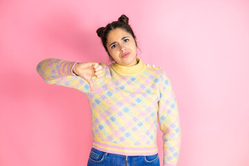 Young beautiful woman wearing casual sweater over isolated pink background with angry face,...