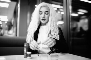 Portrait of a young beautiful blonde girl indoors. Black and white photo.