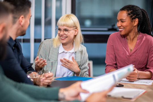Office colleagues having discussion during meeting in conference room. Group of men and women in modern office.