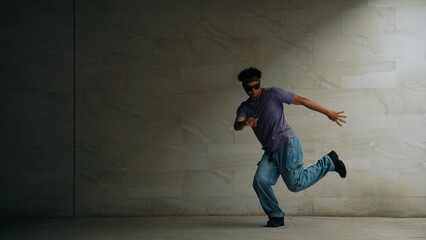 Skilled smart street dancer practice b-boy movement in building with gray background. Young...
