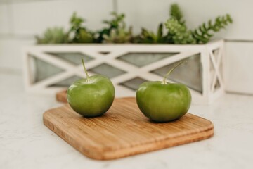 Close up of Green Tomatoes on a Cutting Board in a White Kitchen - Cacti Plant, White Quartz...