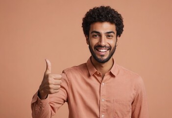 A man with curly hair in a casual pink shirt giving a thumbs up, with a friendly demeanor against a peach backdrop.