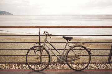 Fototapeta premium bicycle on the beach in the morning. A bicycle stands at a metal railing against the background of the sea. Bicycle in front of a beach at Mediterranean seashore in Italy.