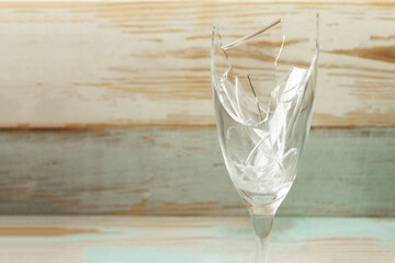 Broken champagne glass on wooden background. Copy space, closeup