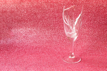Broken champagne glass on pink glitter background, copy space