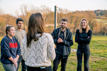 Group of friends listening and laughing at the speech of a girl in a white sweater