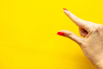 Closeup view of female hand forming gesture Little bit. Isolated on bright yellow background.
