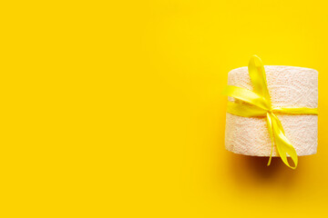 toilet paper roll wrapped in gift bow on bright yellow background. Covid19 concept. Copy space for...