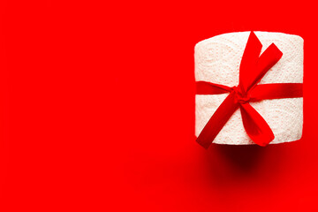 toilet paper roll wrapped in gift bow on bright red background. Covid19 concept. Copy space for the...
