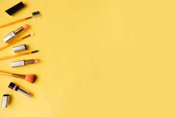Set of pink lipsticks and makeup brushes on bright yellow background flat lay top view minimal....