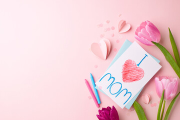 Crafted with love: a mother's day homage. Top view shot of pink tulips, a child's drawing saying 'I love mom', crayons, paper hearts on soft pink background with space for sweet dedications