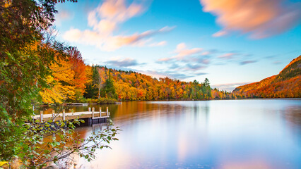 Lac-du-missionaire, Canada: Oct.10 2022: Morning fog on the lake of Lac-du-missionaire with colorful leaves in Quebec in a sunny autumn day - obrazy, fototapety, plakaty