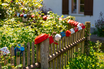 Colorful metal mugs hang on an old wooden fence in a Bavarian village