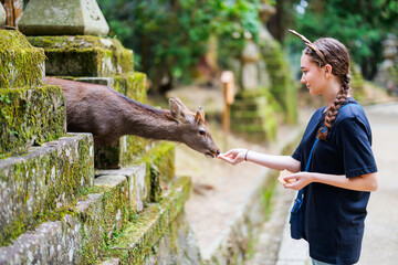 Teenage girl feeding deer in Nara