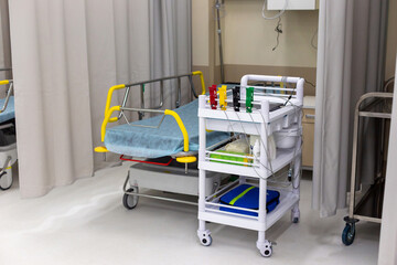 Modern hospital room equipped with a patient bed and a medical trolley with supplies