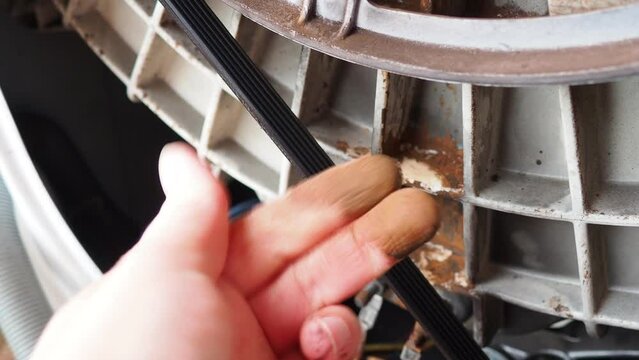 Damage to bearing unit in the washing machine. Demonstration by hand of rusty stains on the tank and bowl of the washing machine with the back cover removed. Service repair of household appliances.