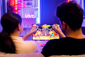Couple or friend buddy joyful player video game on TV using joysticks to bring together at back...
