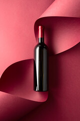 Fototapeta premium Bottle of red wine on a red background.