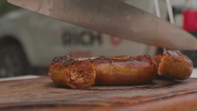 Chef cutting homemade sausage (chorizo), extremely rich and spicy. Paraguayan Chaco. Slowmotion