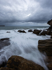 Wave water flowing into the rocky channel at the beach.
