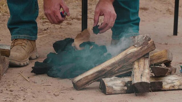 Man rotating charcoal and firewood  to grill a Paraguayan barbecue