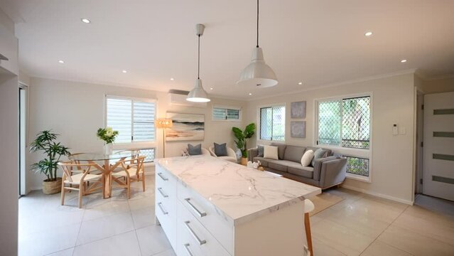 Push past wall to reveal interior kitchen island and open air living room in tropical modern home