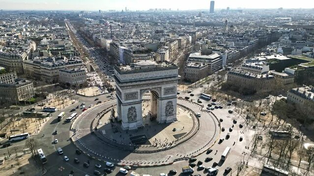 Triumphal arch or Arc de Triomphe and car traffic on roundabout with Paris cityscape, France. Aerial orbiting