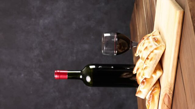 Chilean wine glasses and bottle and empanadas variety. Chile Food background. Fresh ingredients on wood. Selective Focus, vertical video.