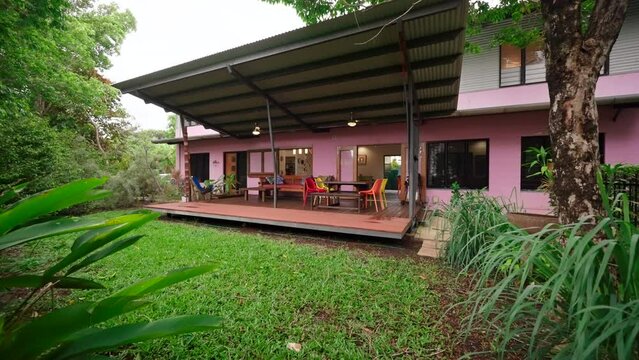 Push in past tropical foliage to reveal vibrant colorful tropical home veranda with open air seating