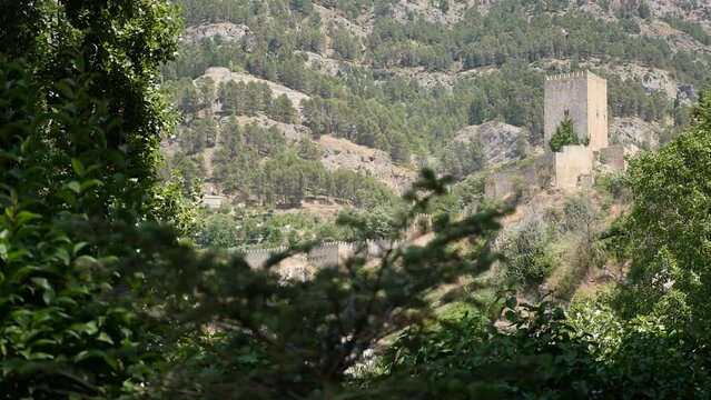 CAZORLA CASTLE AMONG TREES AND MOUNTAINS IN THE BACKGROUND
