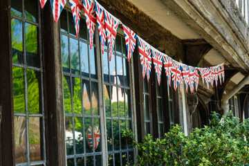 CLOSE UP: String of Union Jack flags strewn under wooden beams of an old house