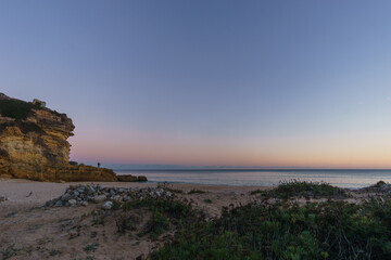 Beach and rock formation in front of the atlantic sea in evening twilight after sunset at Figueira beach, Vila do Bispo, Algarve, Portugal