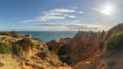 Tourist standing on golden rock cliffs at the coastline of the Atlantic Ocean with near the Cave of...