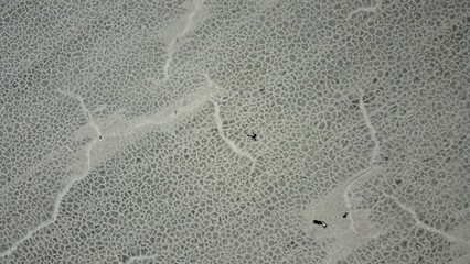 Aerial view of a people reclining on a dry, cracked sandy landscape
